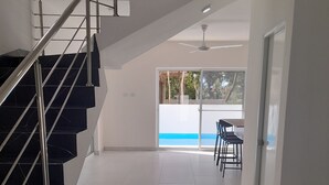 Ein modernes Interieur mit einer schwarzen Marmortreppe, weißen Fliesenböden und Blick ins Freie durch eine Glastür.