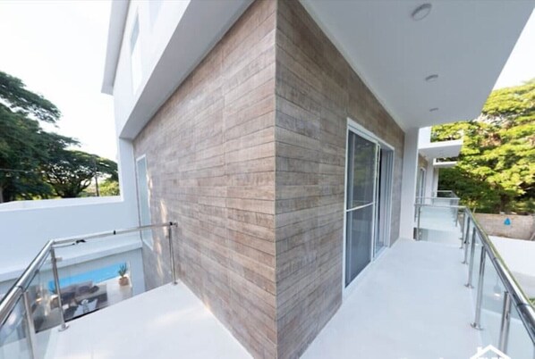 A modern building with a glass balcony, a pool, and a wooden facade.