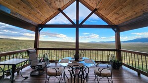 Un espace extérieur abrité, aménagé avec une table et des chaises, offrant une vue sur un vaste paysage.
