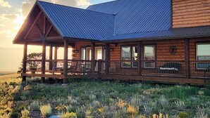 Une grande cabane en bois dotée d’un porche couvert et d’un toit métallique à pente.