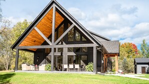 Een modern huis met een groot houten terras, een overdekte patio en een ruime buitenruimte met zitplaatsen.