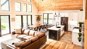 Een moderne keuken met een centraal eiland, houten plafond en grote ramen.