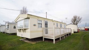 A row of mobile homes with a fenced deck area. - Pets go Free Family 3 Bed Caravan With Decking (King's Lynn)