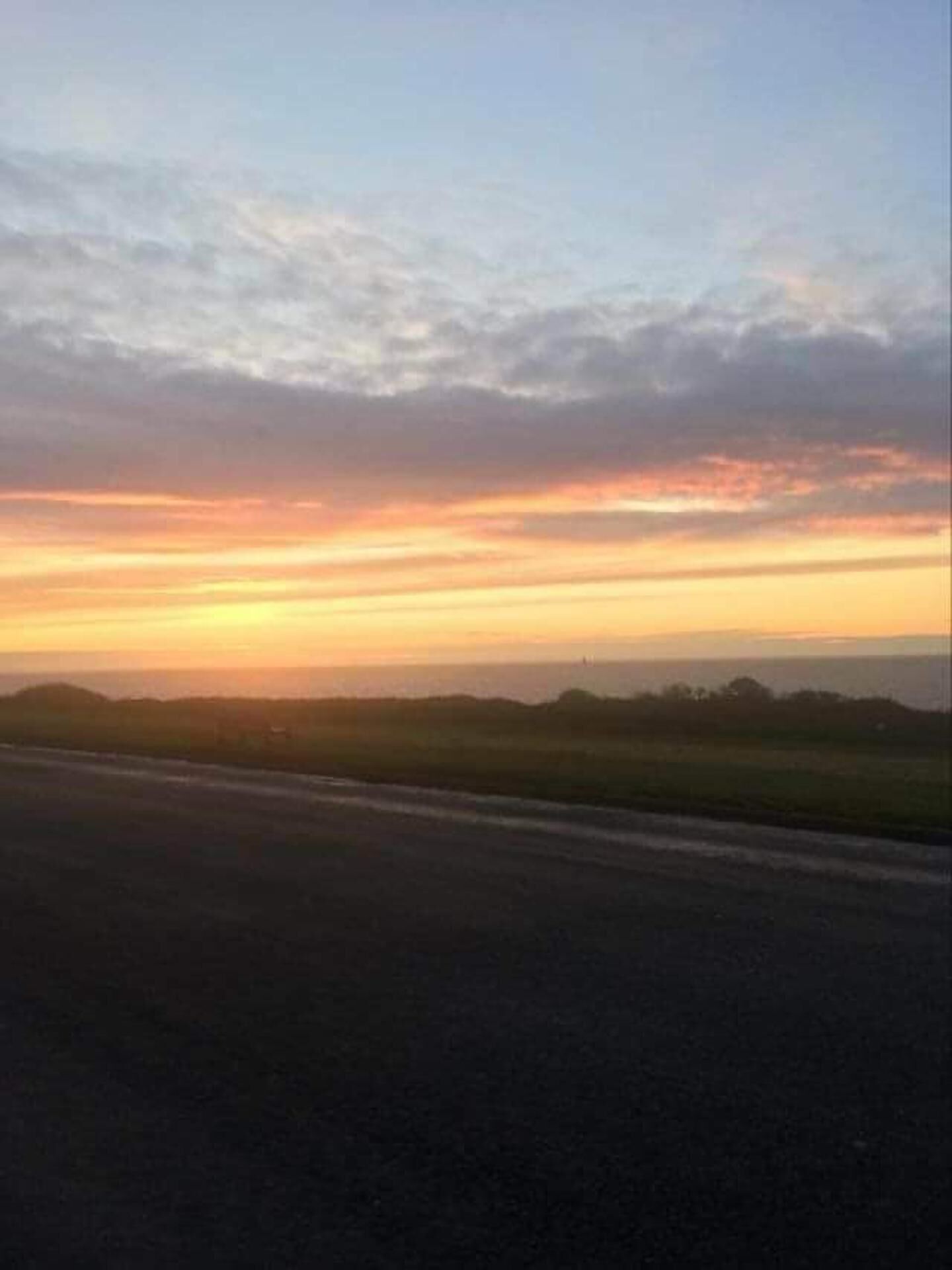 A sunset over a flat landscape with a road in the foreground.