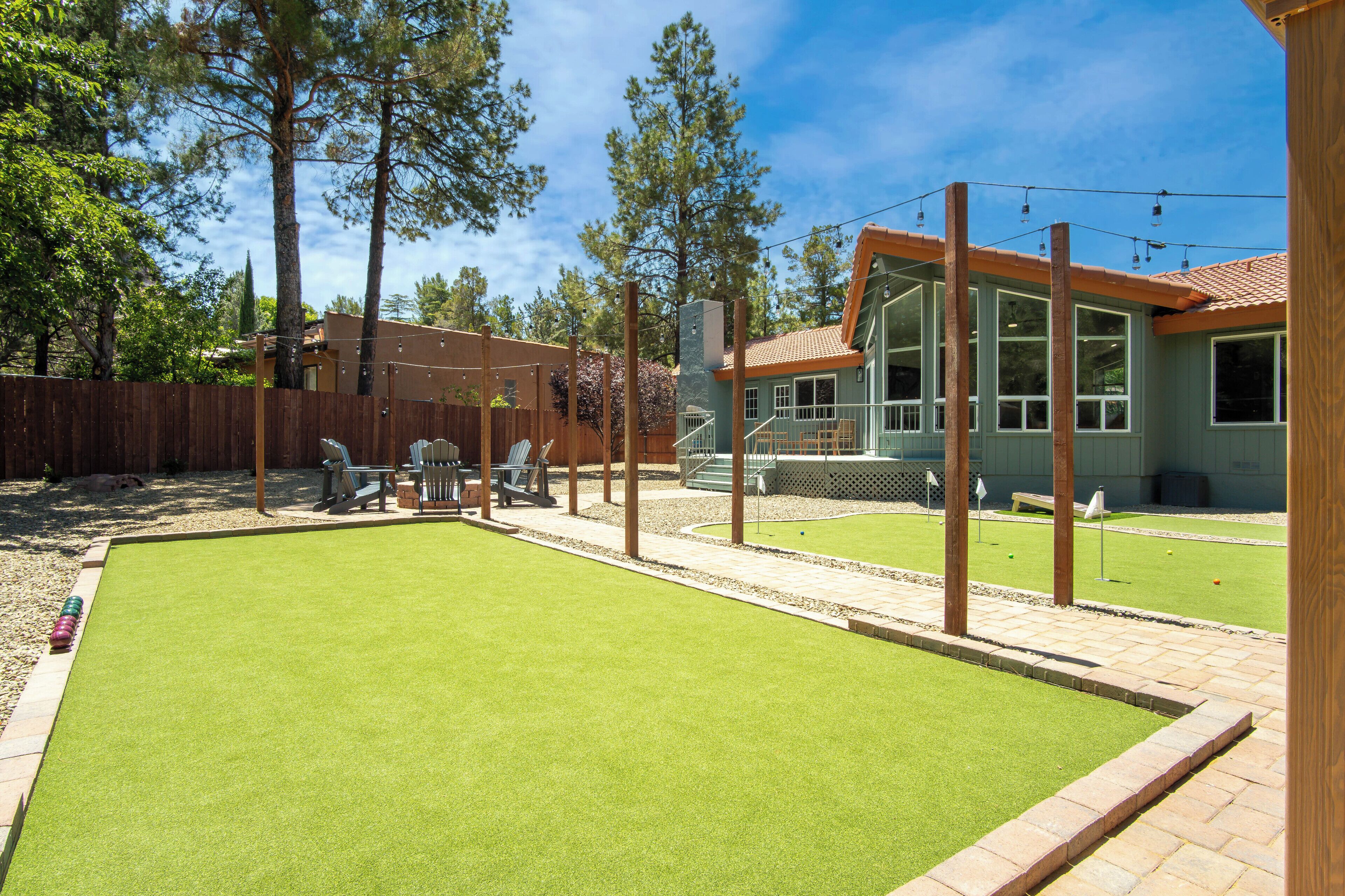 A backyard with a green lawn, a wooden deck, and a building with large windows.