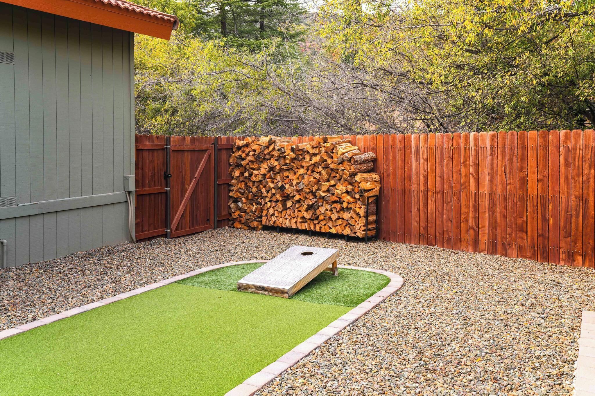 Ein Garten mit einer Holzterrasse, einem Holzstoß und einer Disc-Golf-Abwurfstelle.
