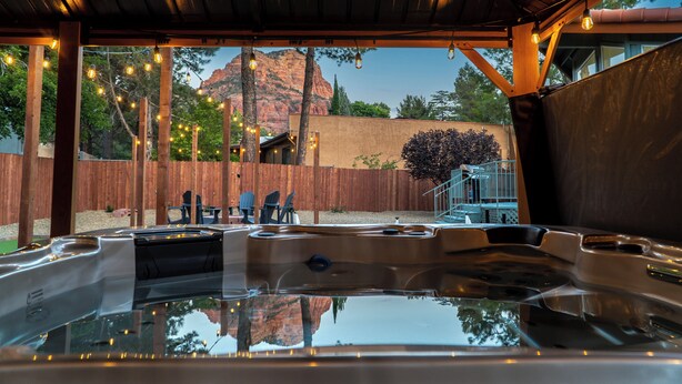 A hot tub area with wooden beams, string lights, and a view of a mountain. - Doodlebug de Sedona • Amenity galore (Sedona)