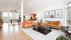 A spacious living room with a large sofa set, a coffee table, and a billiards table. There are framed artworks on the wall and a view of the outdoors through large windows. - Doodlebug de Sedona • Amenity galore (Sedona)