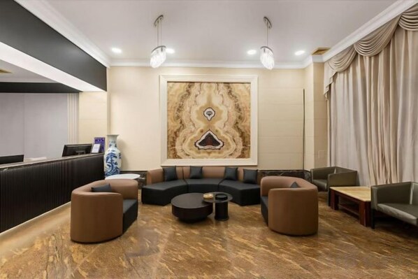 A modern lobby with a reception desk, a large abstract wall art, a sectional sofa, and a coffee table.
