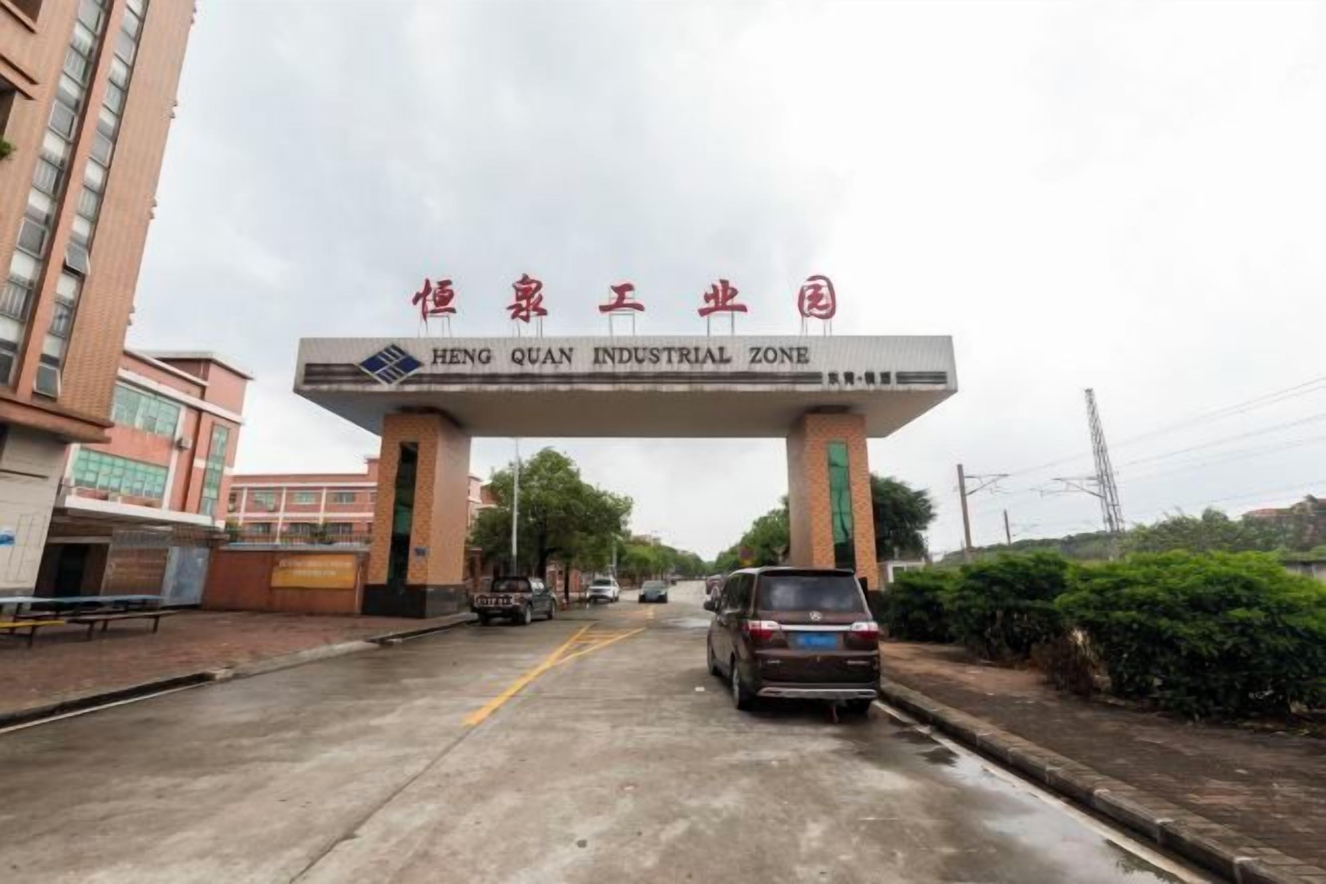 A gate with a sign reading 'HENG QUAN INDUSTRIAL ZONE' and a vehicle passing through.