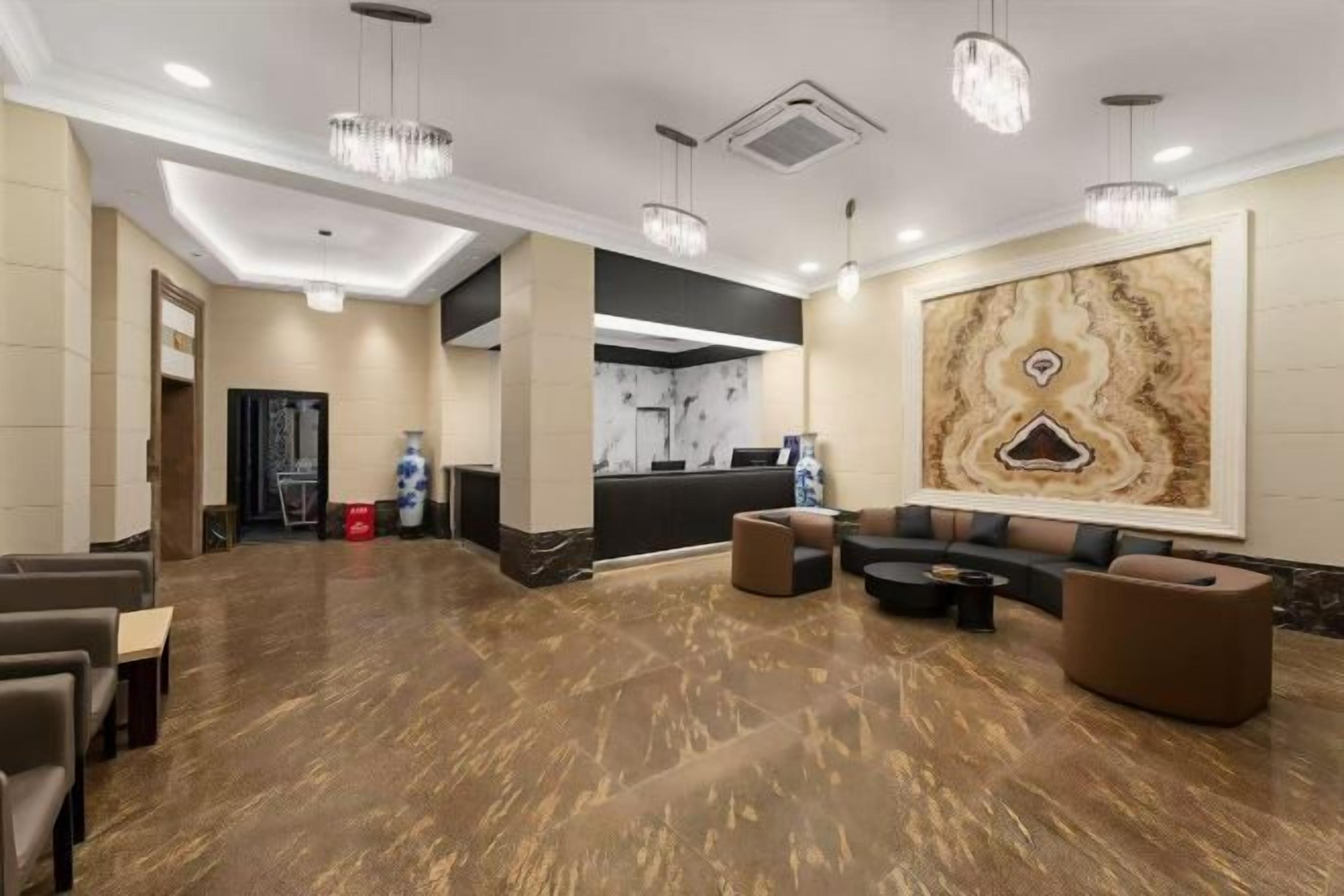 A spacious lobby with a reception desk, seating area, and a large abstract artwork on the wall.