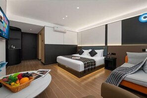 A modern hotel room with a large bed, a sofa, a TV, and a breakfast bar.
