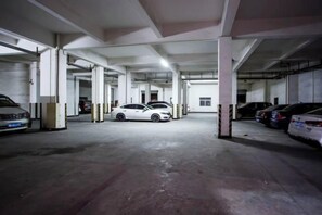 An indoor parking garage with multiple cars parked, concrete pillars, and a flat ceiling.