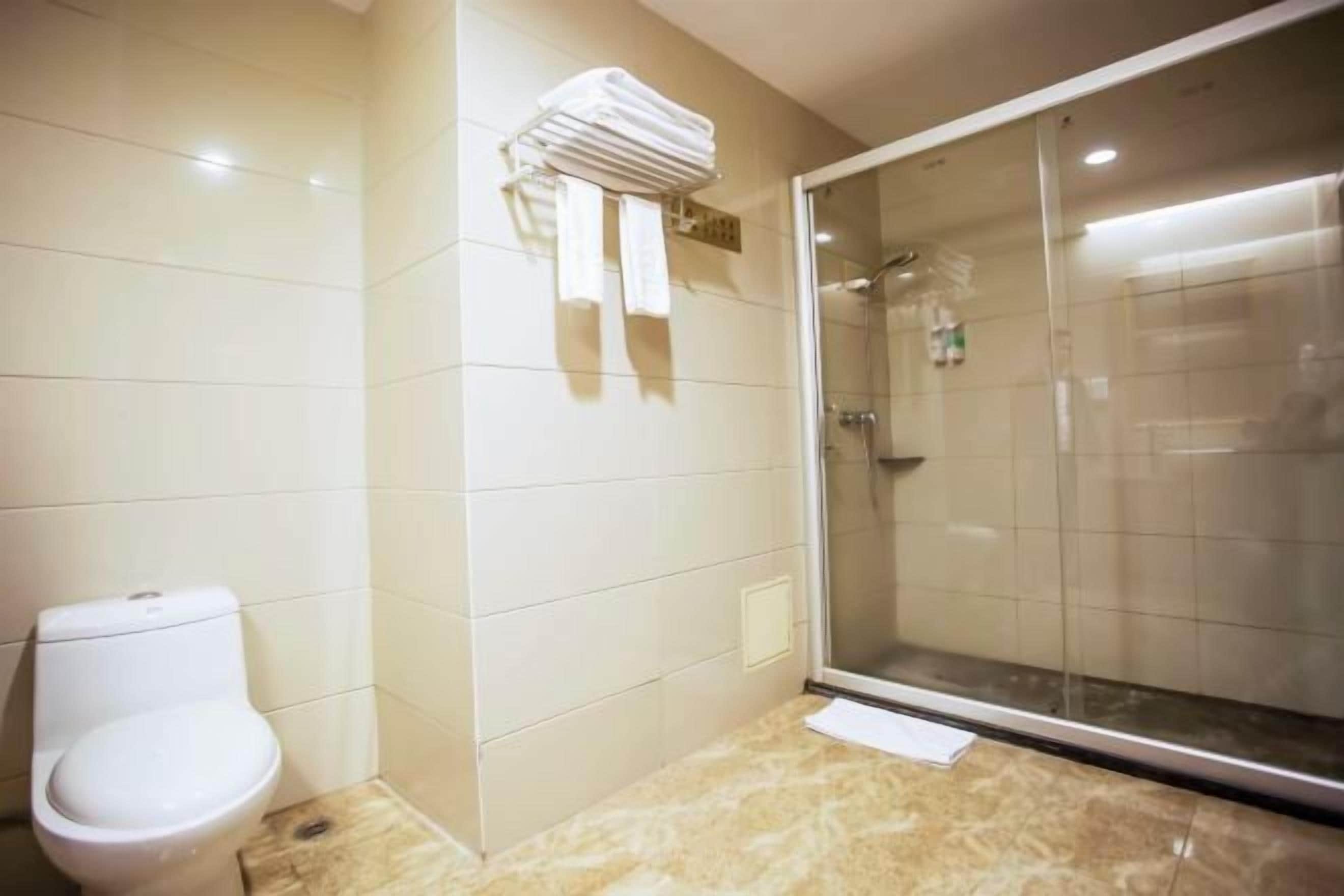 A bathroom with a toilet, a glass-enclosed shower, and a towel rack.