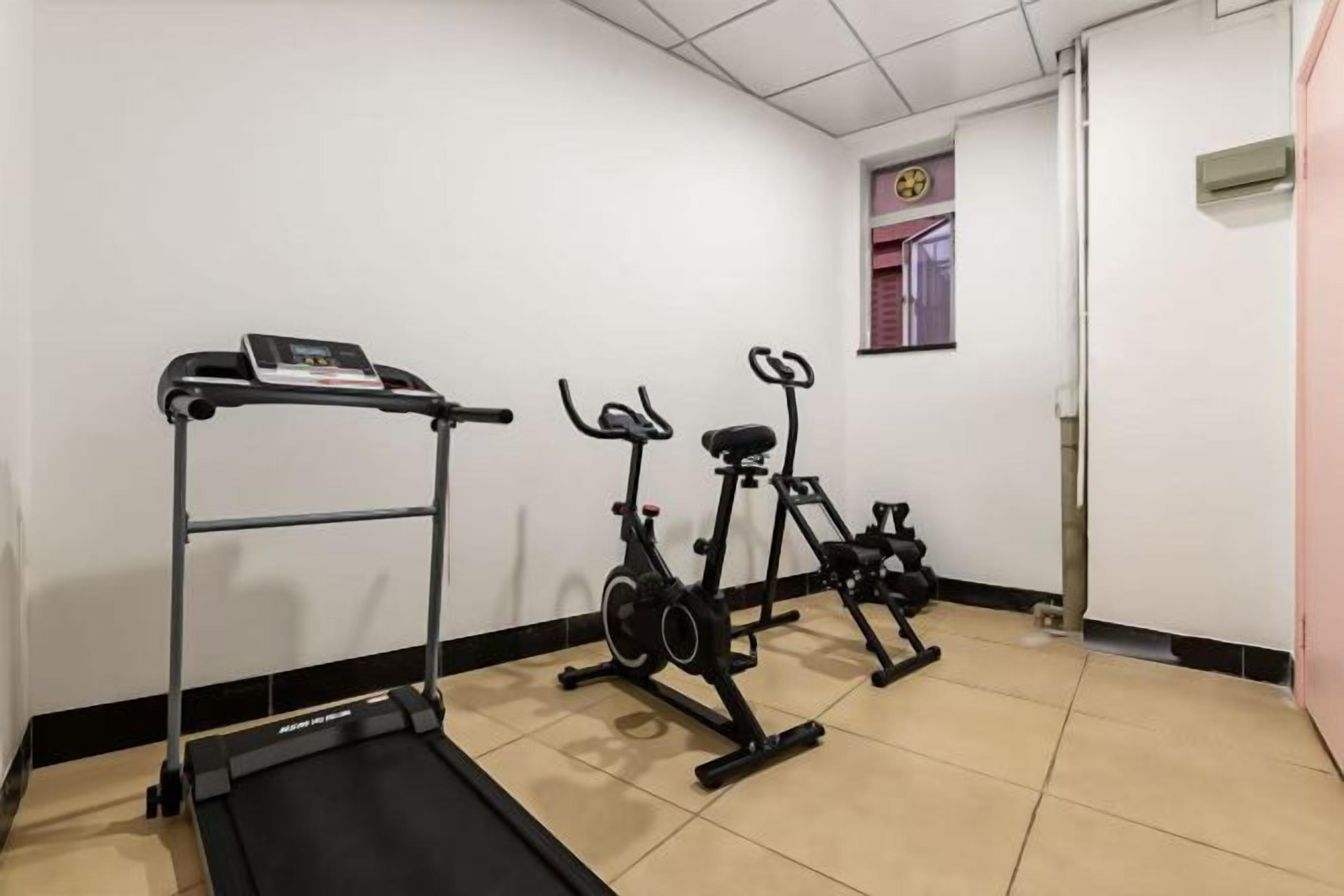 A fitness room with a treadmill, stationary bikes, and a weight bench.