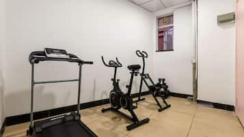 A fitness room with a treadmill, stationary bikes, and a weight bench.