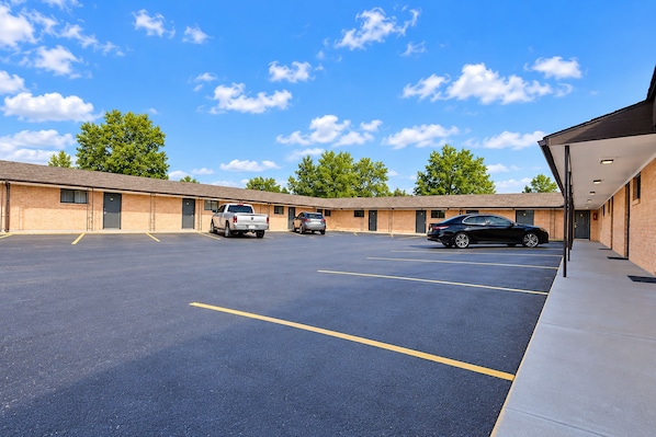 A motel with a parking lot, a covered walkway, and a building with a flat roof.