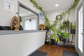 A reception area with a wooden reception desk, a mirror, a sign indicating pet policy, and various potted plants.