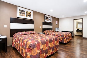 A hotel room with two beds, a nightstand, a mirror, and a framed picture on the wall.