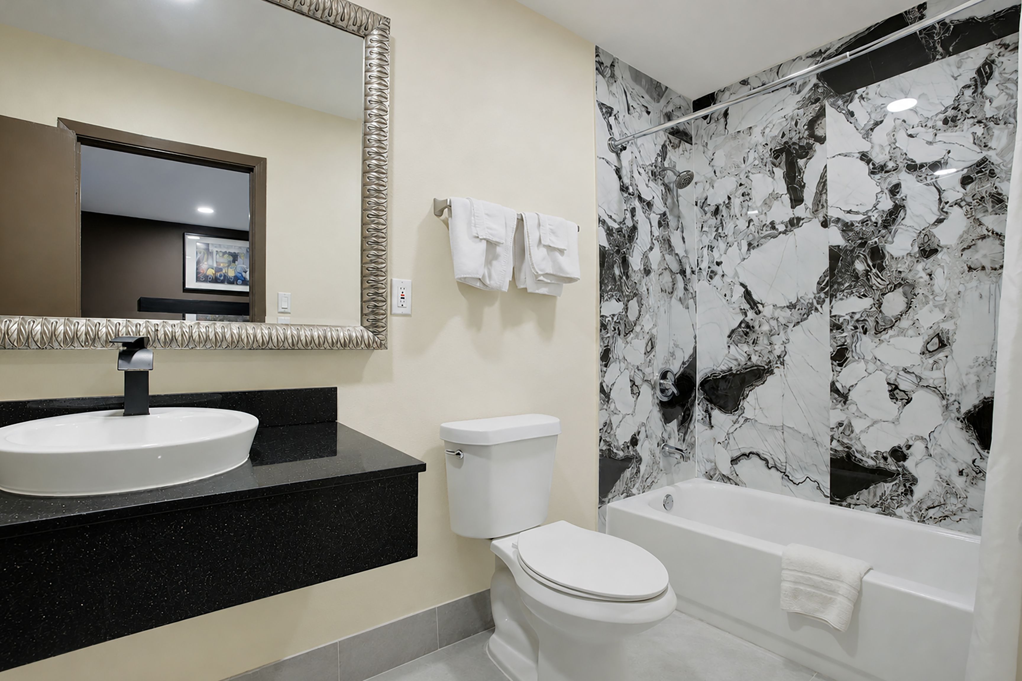 A modern bathroom with a round sink, toilet, and bathtub.