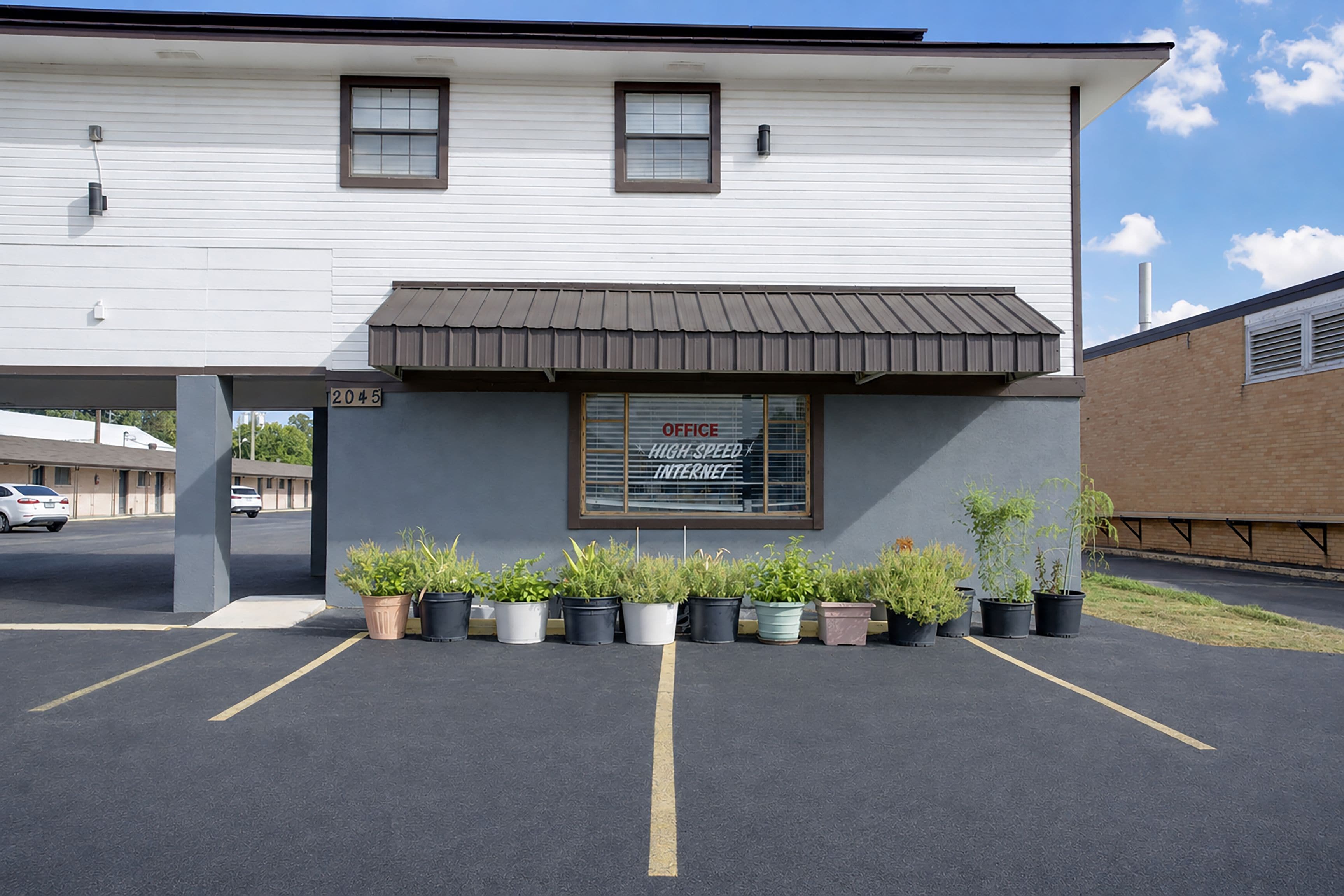 A two-story building with a sign indicating an office and high-speed internet. There are potted plants in front of the entrance.