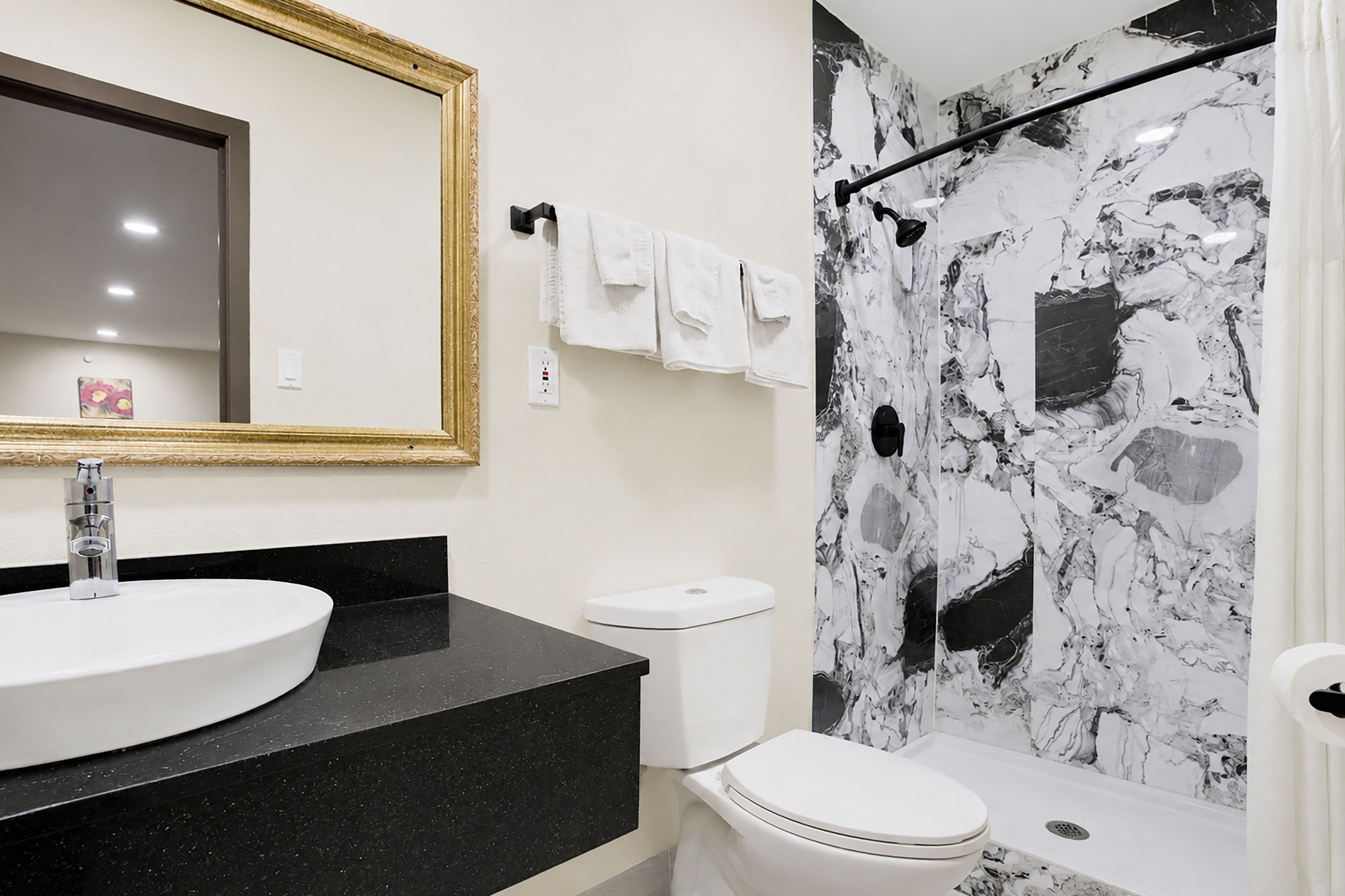 Une salle de bain avec un lavabo rond, des toilettes et une douche aux murs en marbre.