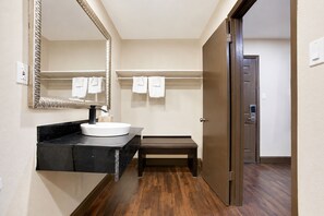 A bathroom with a sink, mirror, towel rack, and a bench.