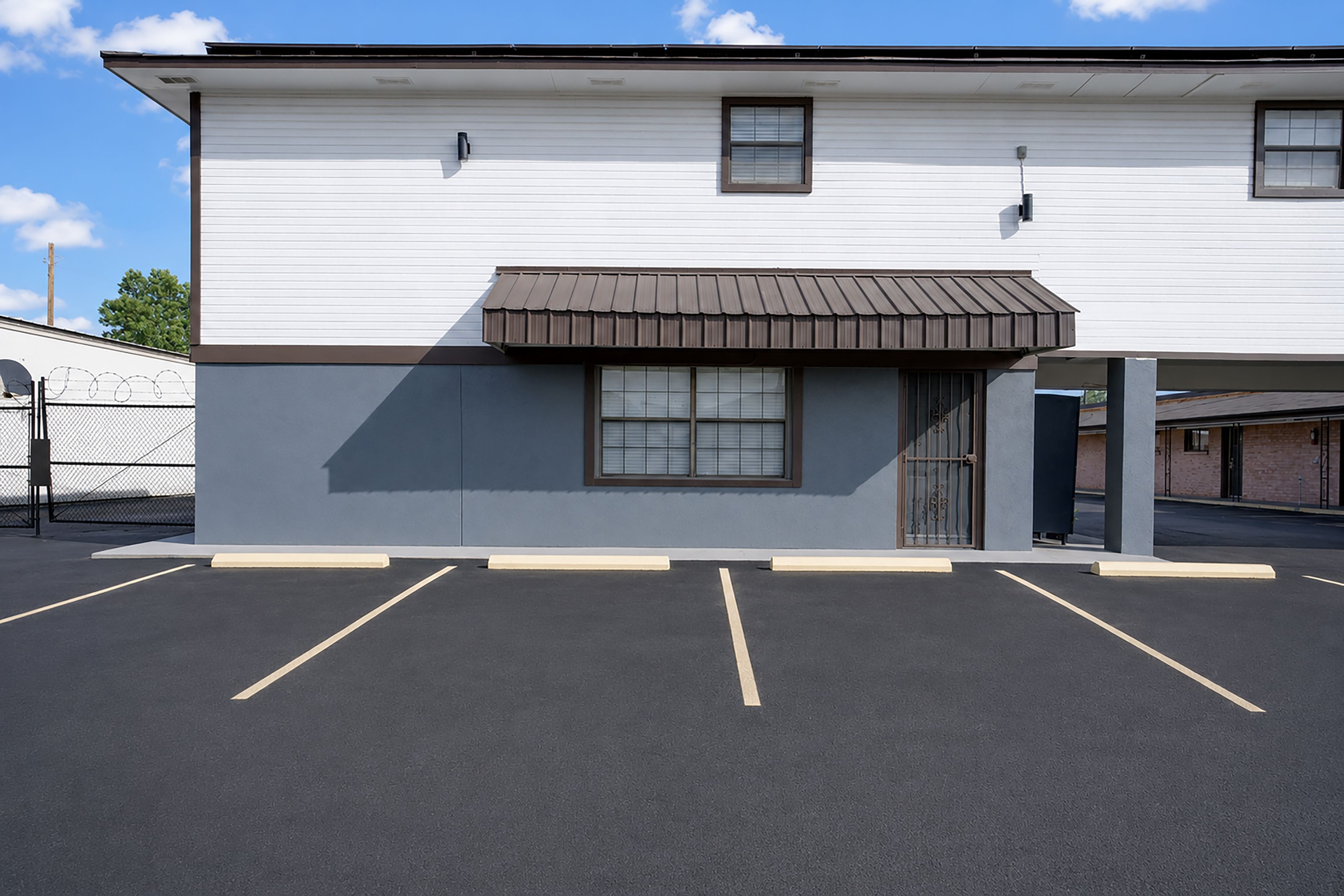 A two-story building with a flat roof, a covered entrance, and a parking lot in front.