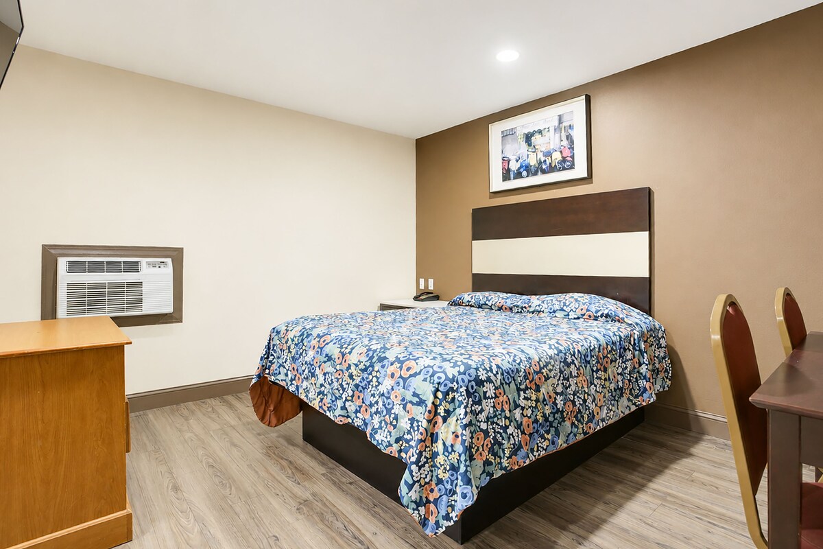 A hotel room with a bed, a desk, and a chair.