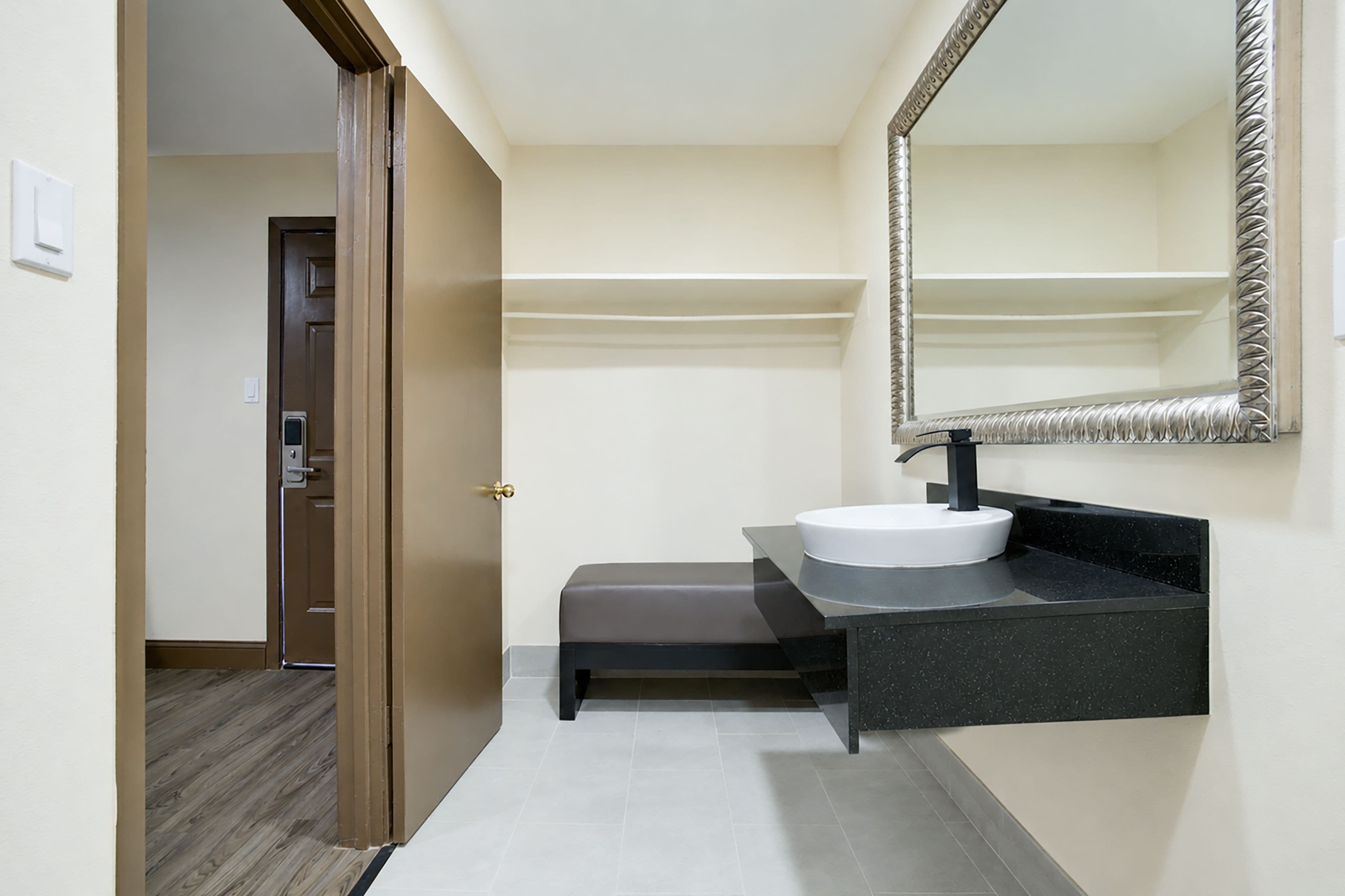 Une salle de bain moderne avec un lavabo blanc, un plan de toilette noir et un grand miroir.