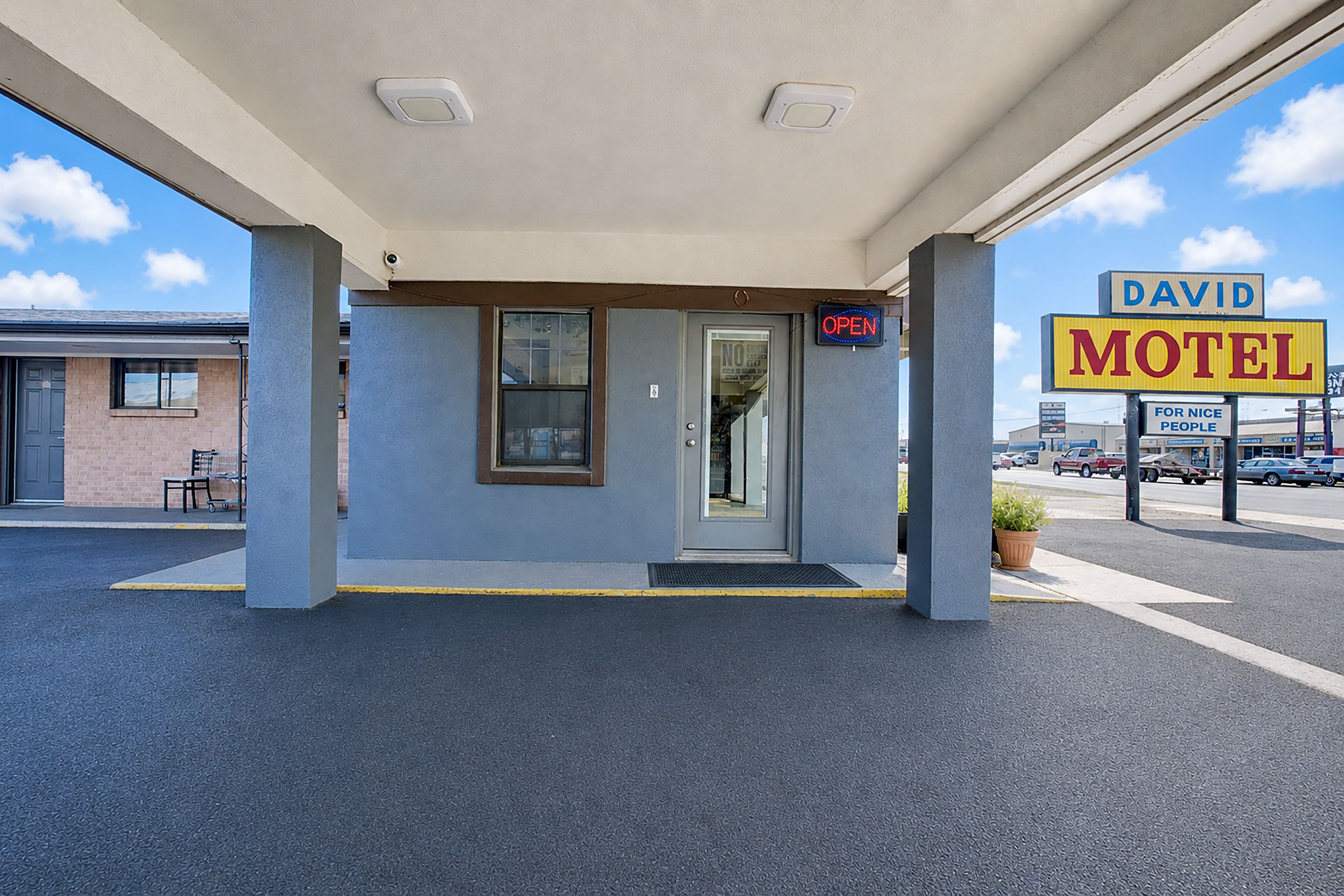 Un motel con entrada despejada, un letrero y un estacionamiento.