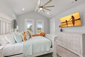 A bedroom with a bed, a ceiling fan, a TV, and a view of the outdoors. - Beach View 4BR Retreat | Soccer Field | Putt-Putt | Pet Friendly (Galveston)