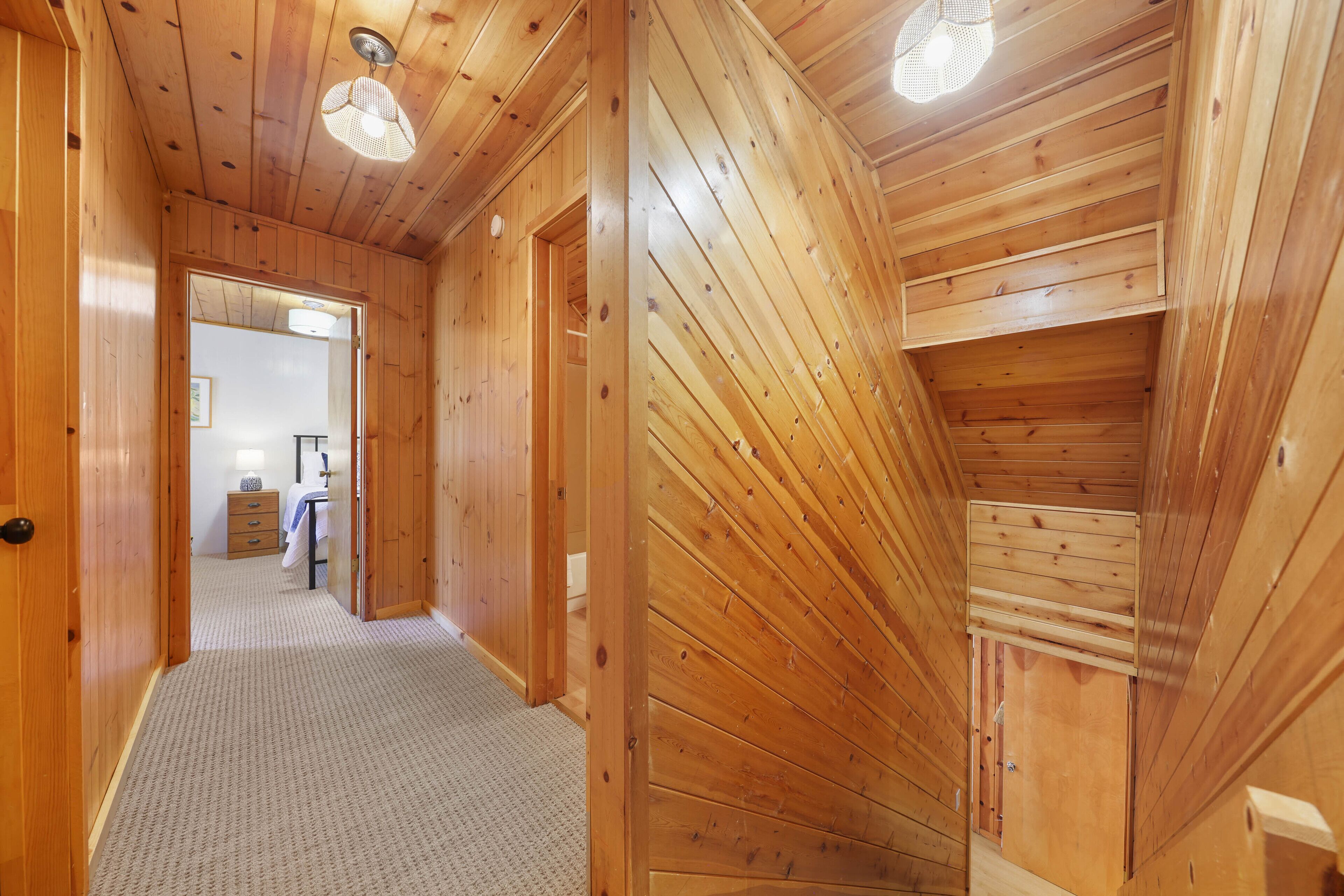 Ein Holzboden-Flur mit Teppichboden, Holzvertäfelung und Deckenventilator.