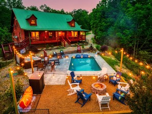 Une cabane en bois avec une piscine, des chaises longues et un foyer extérieur.