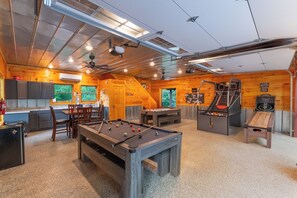 Un interior de madera con mesa de billar, mesa de ping pong y zona de juegos.