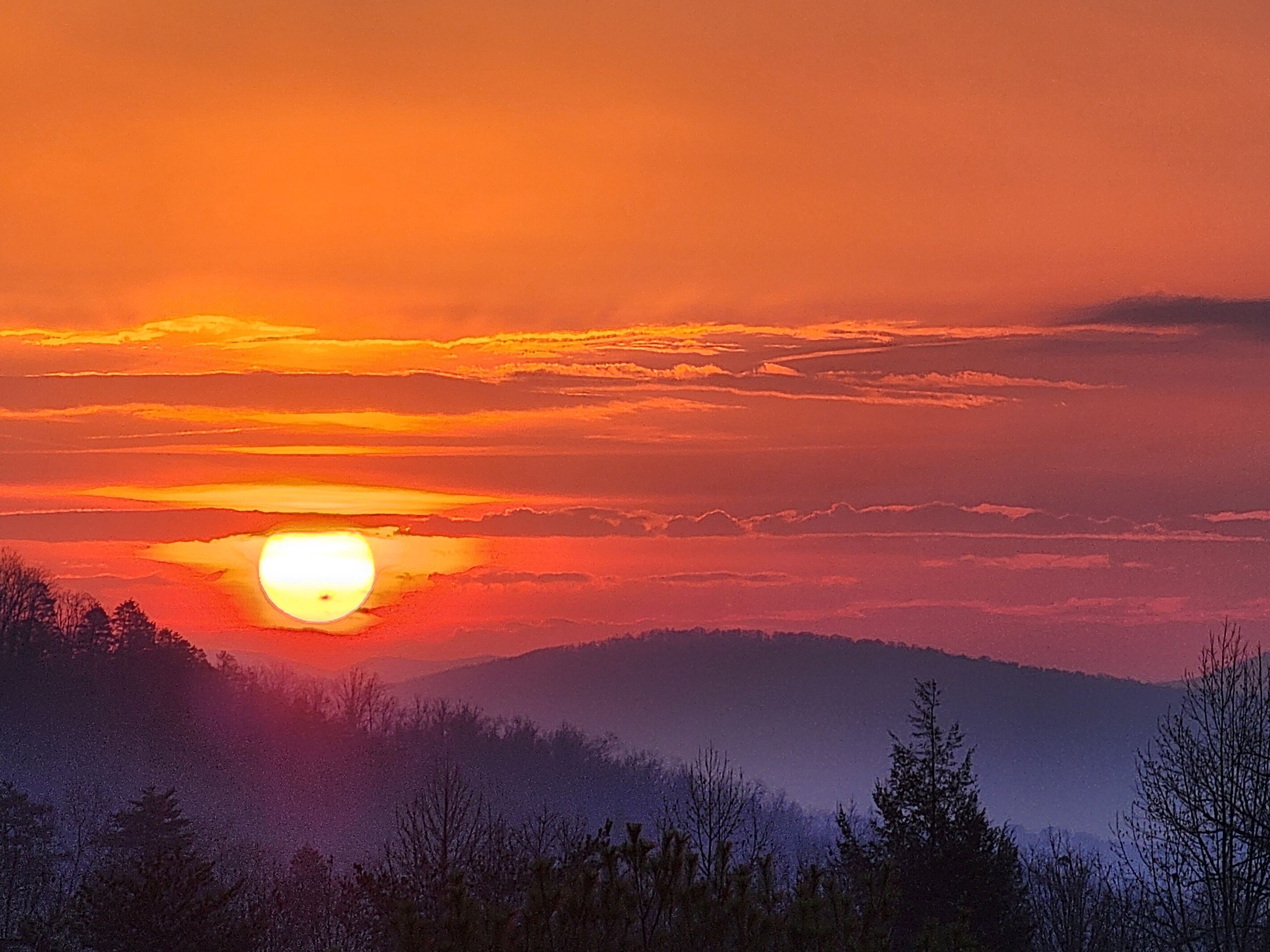 A sunset over a mountainous landscape with a clear sky.