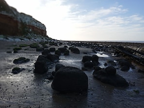 A rocky beach with large boulders and a wooden walkway. - Heacham Beach Caravan - Sleeps 6 - Pets Ok (King's Lynn)