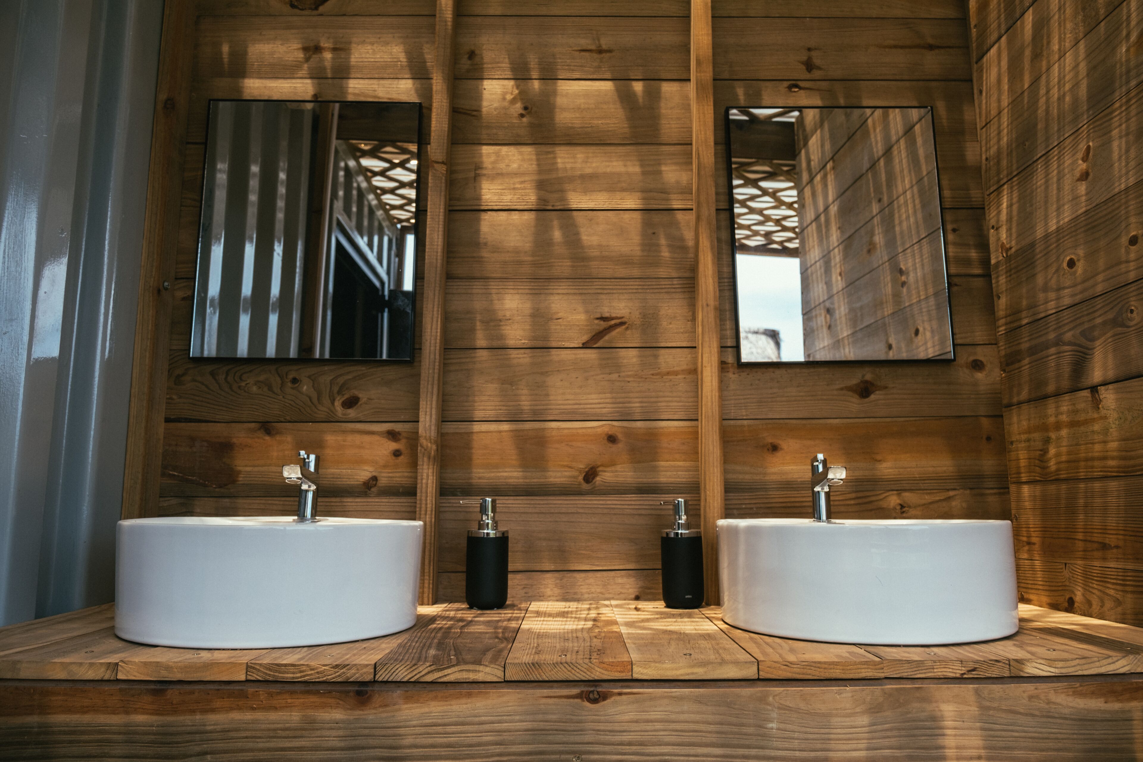 Un baño de madera con dos lavamanos y espejos.