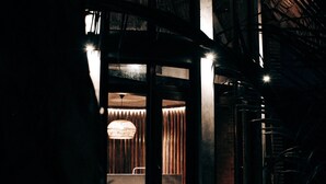 Un interior moderno con una zona de estar circular, una lámpara colgante y una escalera que sube a un nivel superior.