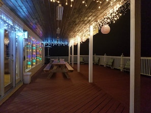 Eine Holzterrasse mit Picknicktisch, Lichterkette und Geländer.