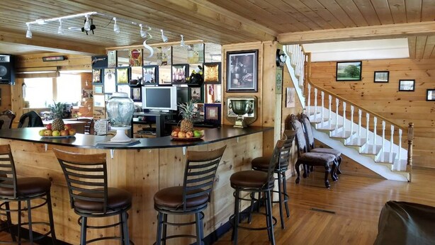Interior em madeira com área de bar, incluindo balcão, cadeiras e quadros nas paredes.