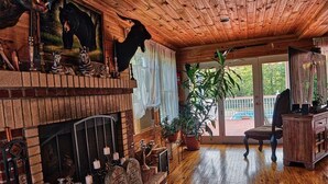 Um quarto aconchegante com lareira, teto de madeira e uma grande janela com vista para um terraço.