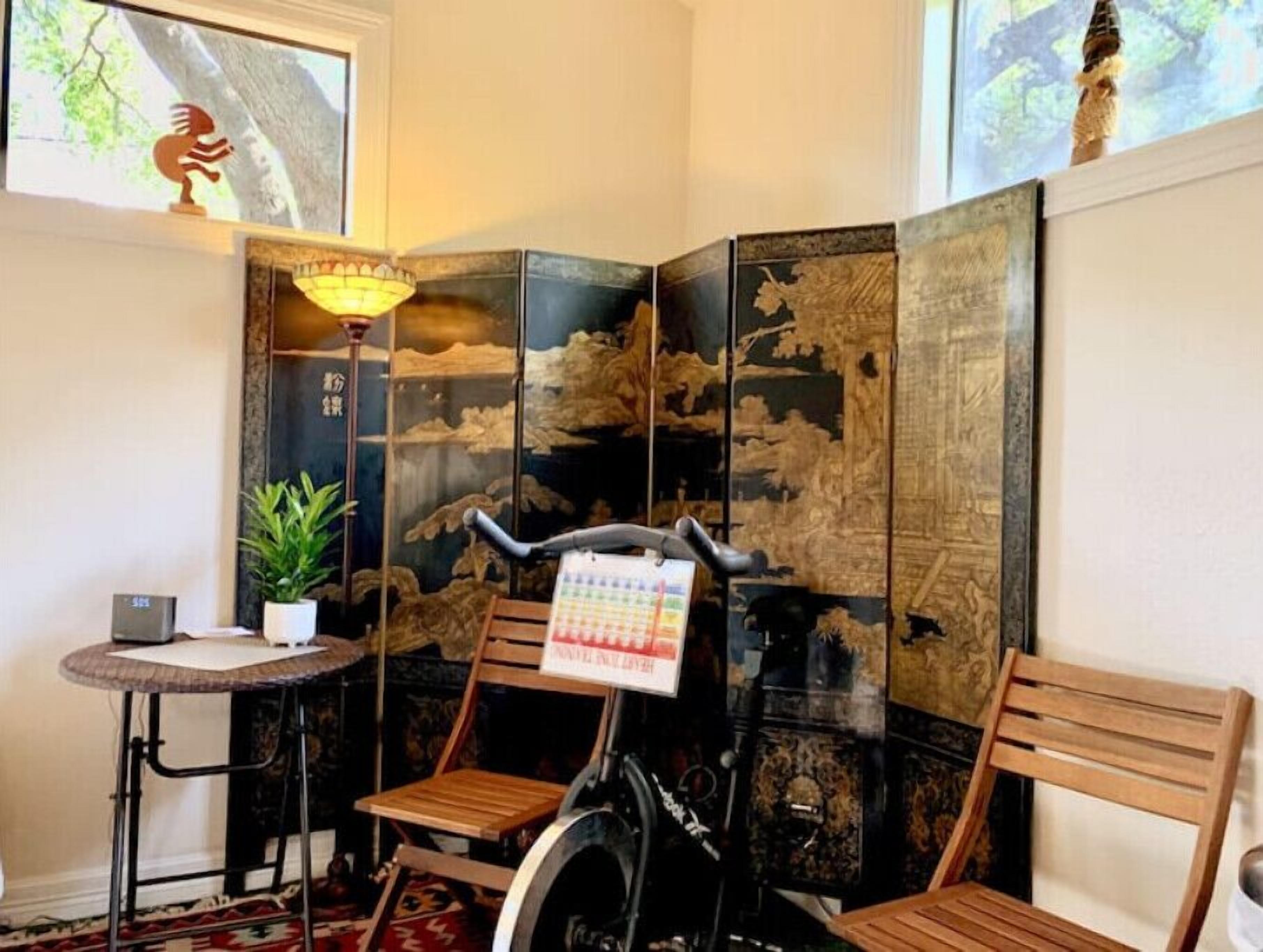 Een hoekzaal met een traditionele Japanse scheidingswand, een fiets, een klein tafeltje met een plant in pot en een stoel.