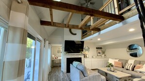 Un vaste espace de vie doté d’un haut plafond, d’une cheminée, d’un canapé, d’une table basse et d’un escalier menant à un niveau supérieur.