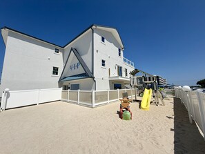 A beachfront hotel with a large building, a playground, and a sandy beach area. - The VIP Family Motel (Wildwood Crest)