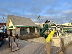 A hotel with a green and yellow slide, a wooden deck, and a building with a green roof. - The VIP Family Motel (Wildwood Crest)