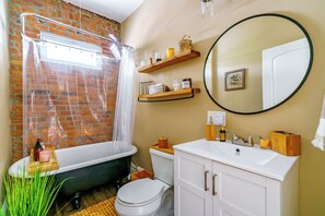 A bathroom with a bathtub, toilet, and white vanity. - The Parkside by Jungle House – Short North Boutique Suites (Columbus)