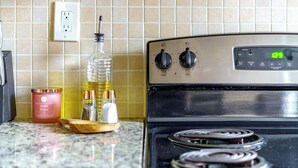A kitchen with a stove, a timer, and a container of sugar. - The Parkside by Jungle House – Short North Boutique Suites (Columbus)