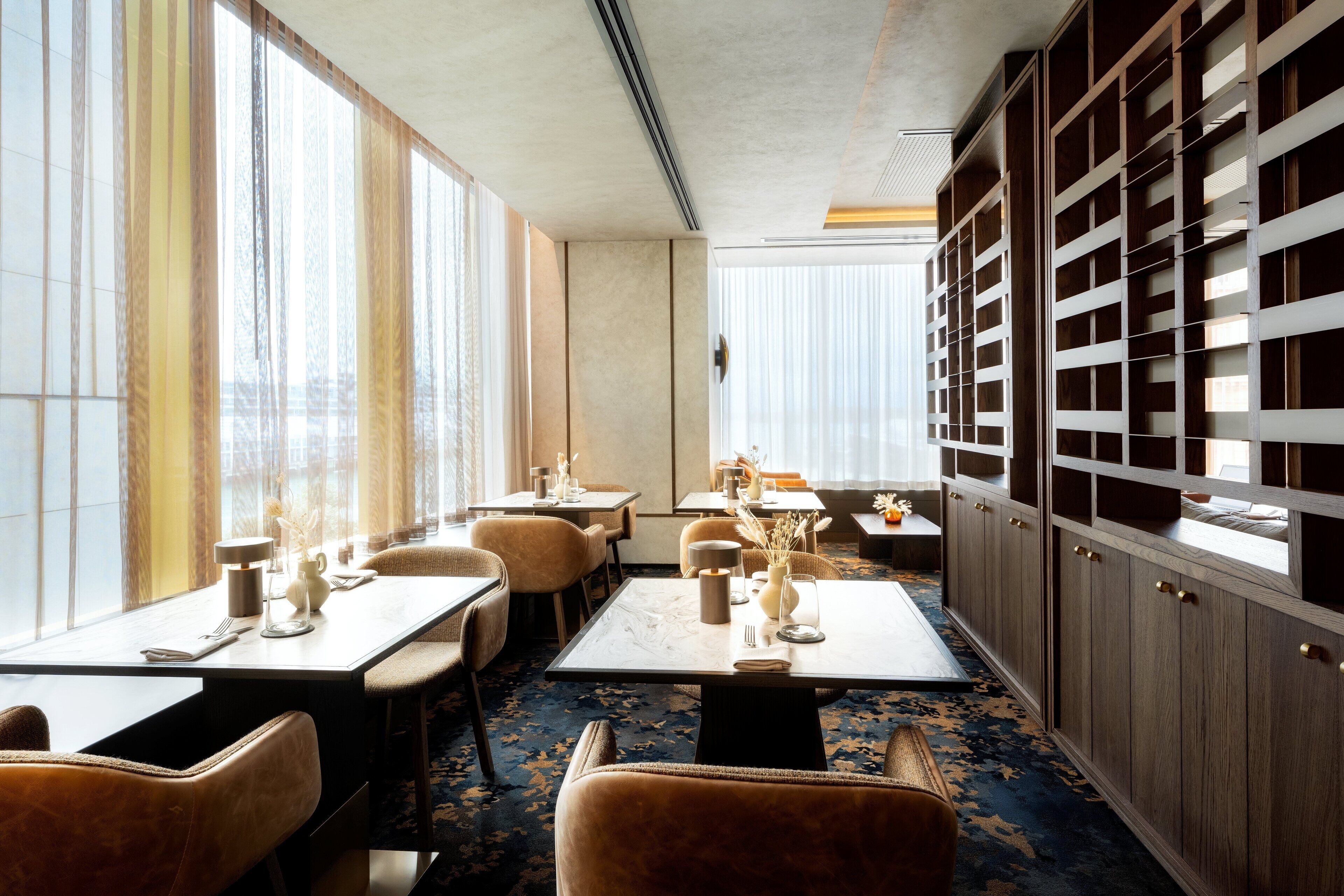 A dining area with tables, chairs, and a large bookshelf.