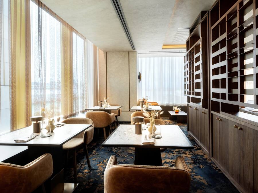 A dining area with tables, chairs, and a large bookshelf.